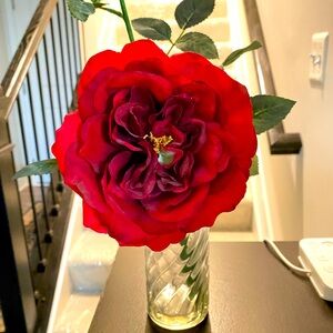 Beautiful red flower glass bottle decor with a rose bud and green leaves.